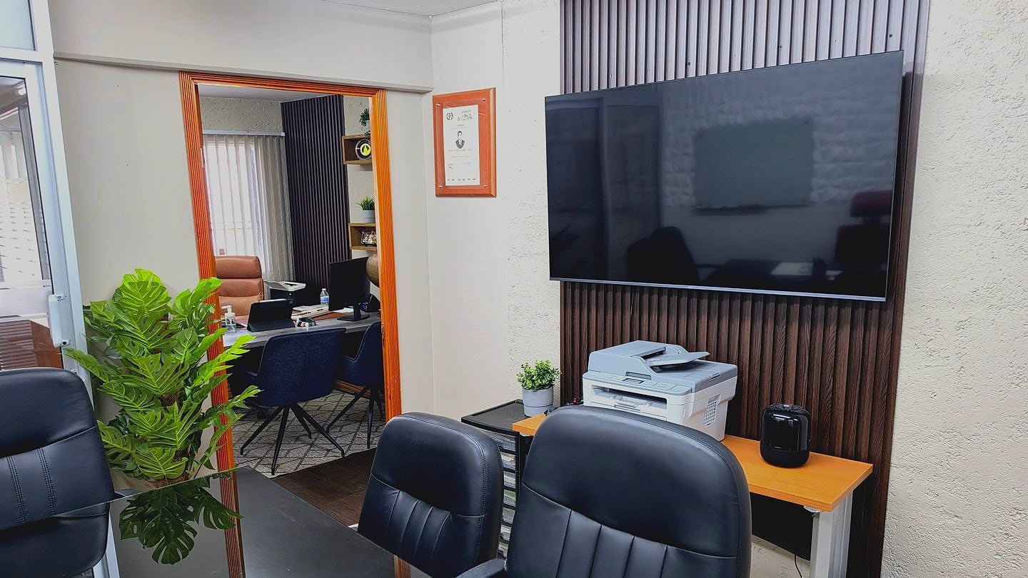 Área de trabajo de GMG Contadores: mesa de juntas de cristal, pantalla para presentaciones, equipo de impresión y acceso a la oficina privada